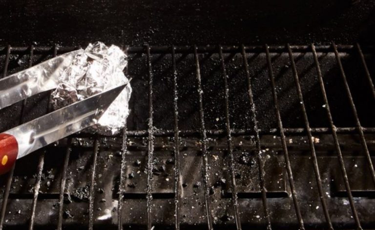 Tongs holding aluminum foil ball for cleaning grill grates