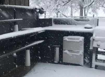 snowing on an outdoor kitchen with a two drawer refrigerator