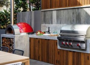 red outdoor pizza oven at the end of outdoor kitchen countertop