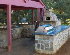 Outdoor kitchen with corner masonry pizza oven pro built