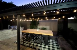large outdoor kitchen and eating area under shaded pergola
